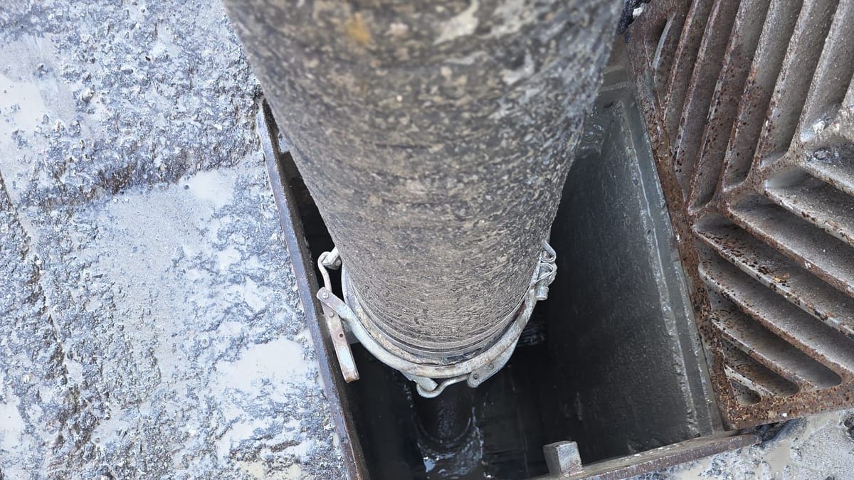 Hydrovac hose lowered into an open catch basin chamber to vacuum out sediment