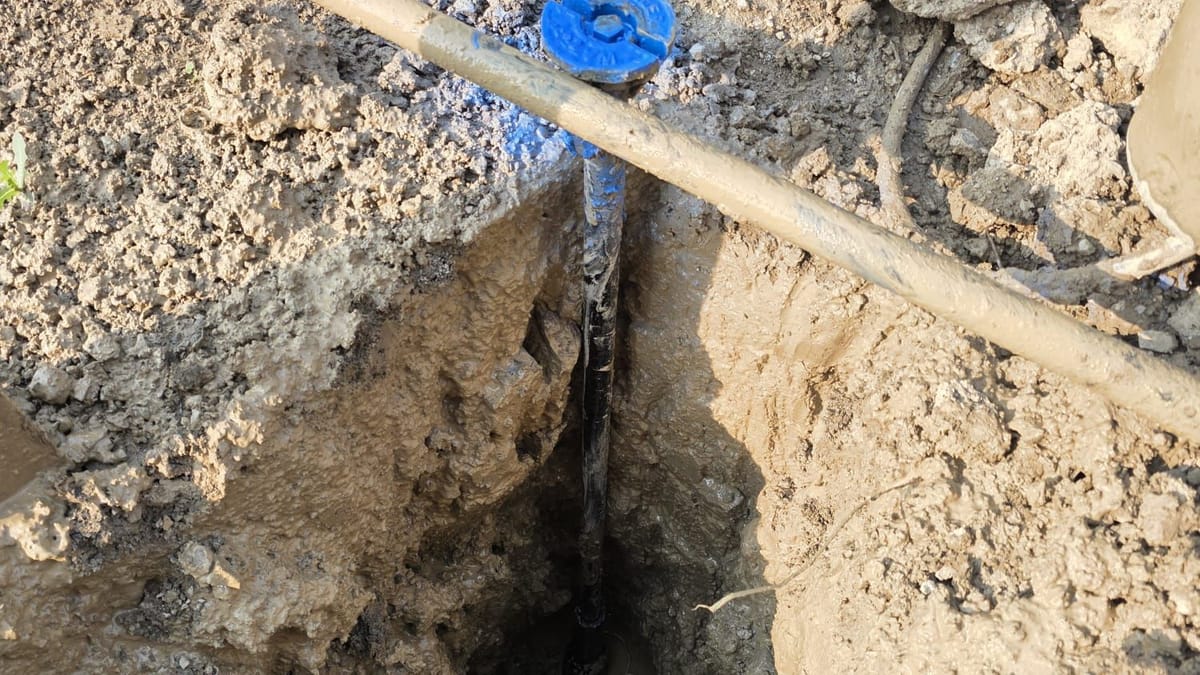 Curb stop and service line exposed in a narrow hydrovac hole with the blue cap at the surface