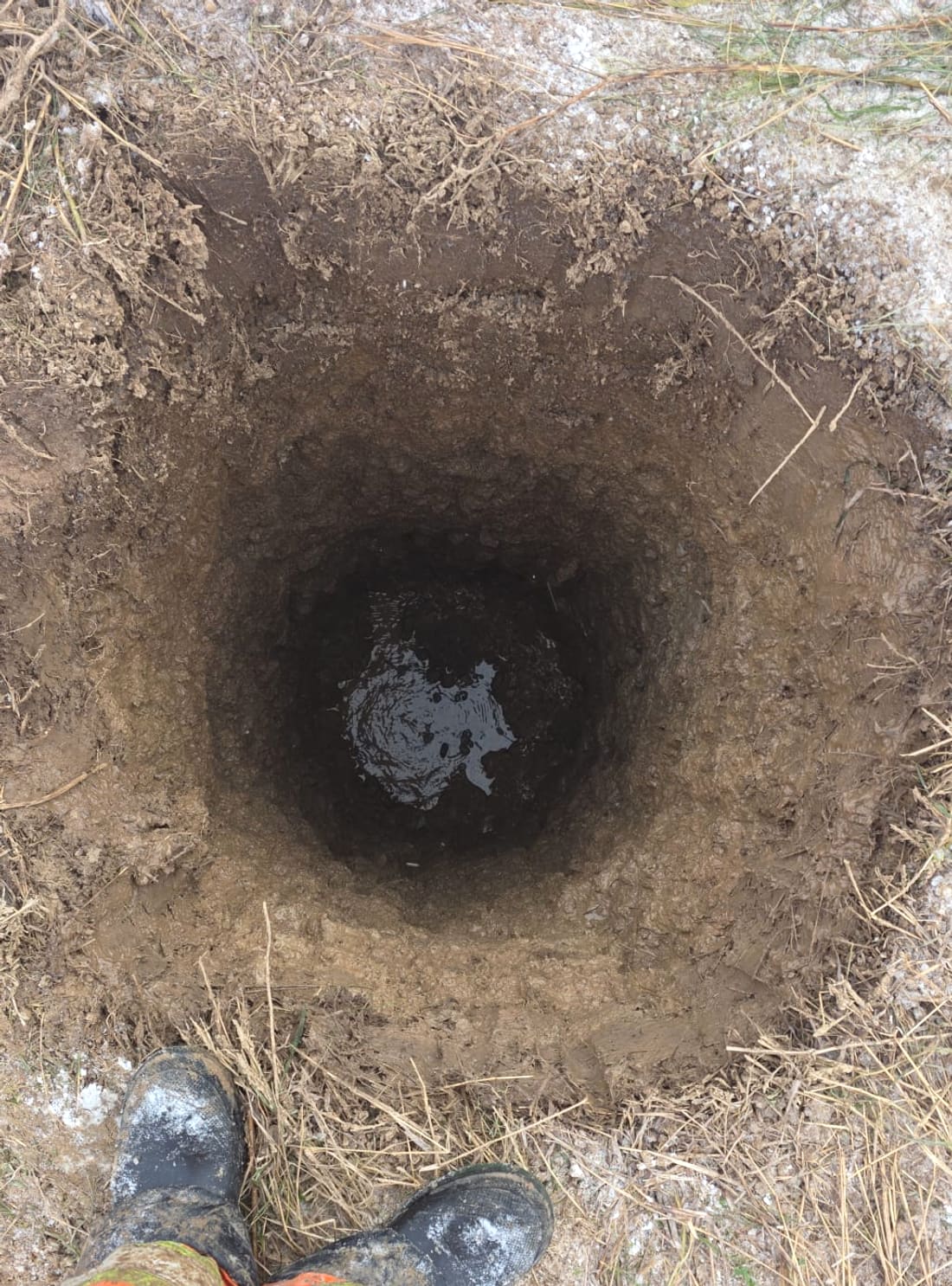 Clean, contained round test pothole dug by hydrovac with the operator standing at its edge